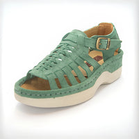 A pair of women's open-toe sandals in a mint suede, featuring cutout straps, a braided front design, adjustable ankle straps with silver buckles, and white soles.
