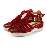 A pair of red suede wedge sandals with cutout straps, a buckle strap, and a beige sole, shown on a white background.