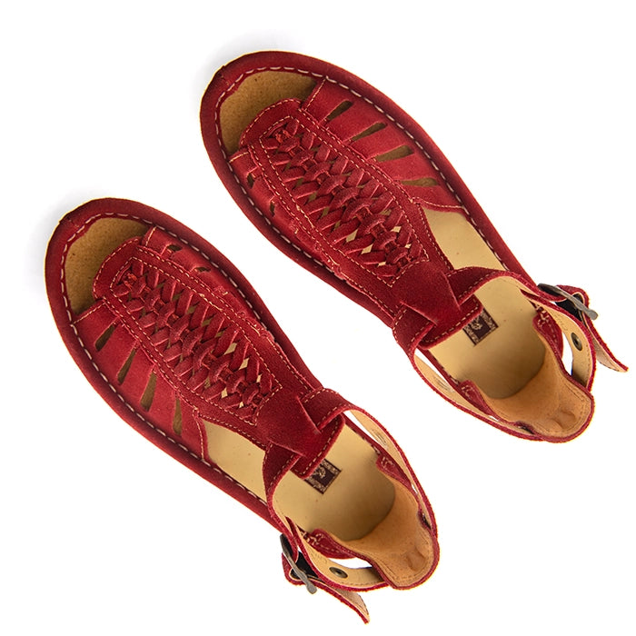 A pair of red suede wedge sandals with cutout straps, a buckle strap, and a beige sole, shown on a white background.