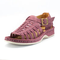 A single shoe with strappy sandals in lilac suede, featuring a cutout design, braided detail across the front, an adjustable ankle strap with a gold-tone buckle, and a low wedge heel. The brand 'Omega' is visible on the buckle.