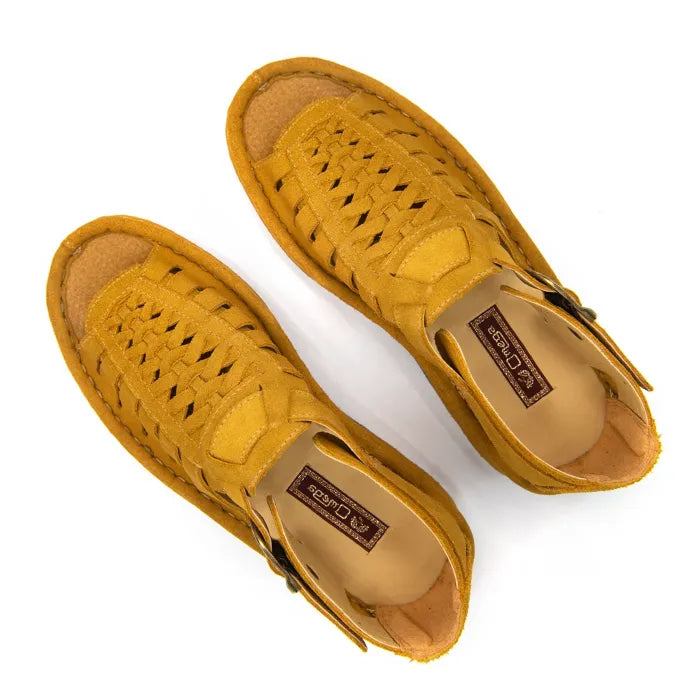 A pair of mustard yellow woven leather sandals with cutout details, displayed from a top-down view on a white background.