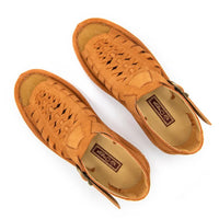 A pair of peach coloured suede sandals with cutout straps, braided detailing, and adjustable ankle buckles, shown on a white background.