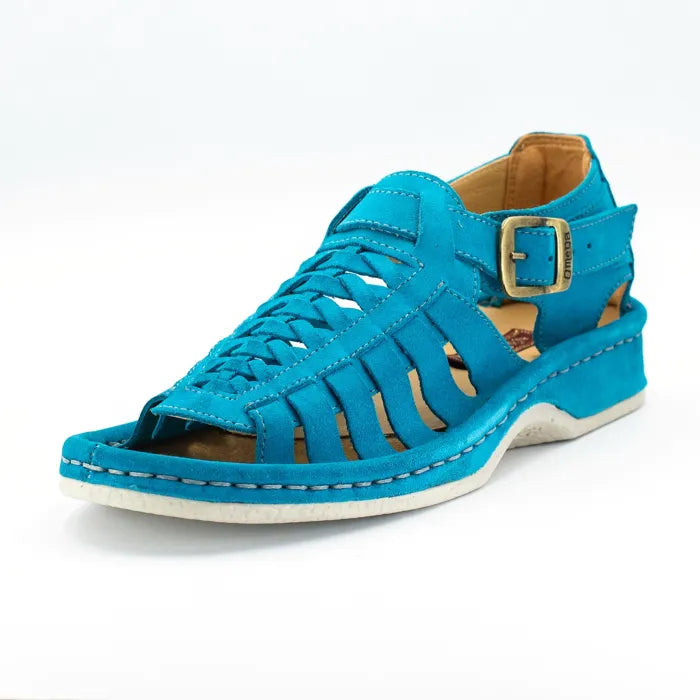 A single sandal in turquoise suede, featuring a multi-cut strap design, an adjustable ankle strap with a gold-tone buckle, and a thick white sole.