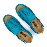 A pair of sandals in turquoise suede, featuring a multi-cut strap design, an adjustable ankle strap with a gold-tone buckle, and a thick white sole.