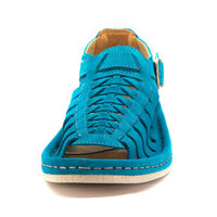 A single sandal in turquoise suede, featuring a multi-cut strap design, an adjustable ankle strap with a gold-tone buckle, and a thick white sole.