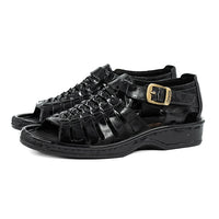 Black sandals with a gold buckle on a white background