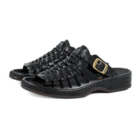 Black slip-on sandals with a gold buckle on a white background