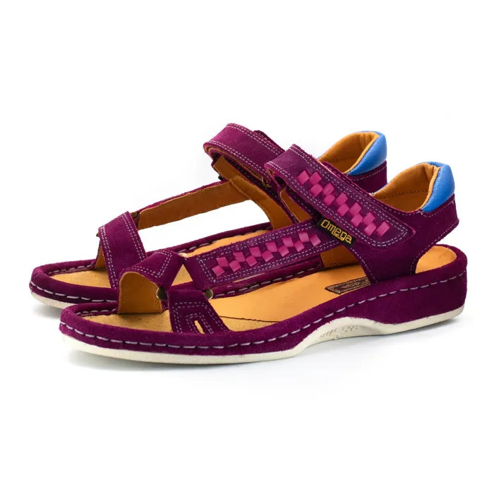A pair of women's wedge sandals in deep cerise suede with woven pattern details on the straps, a tan interior, and blue heel accents, shown on a white background.