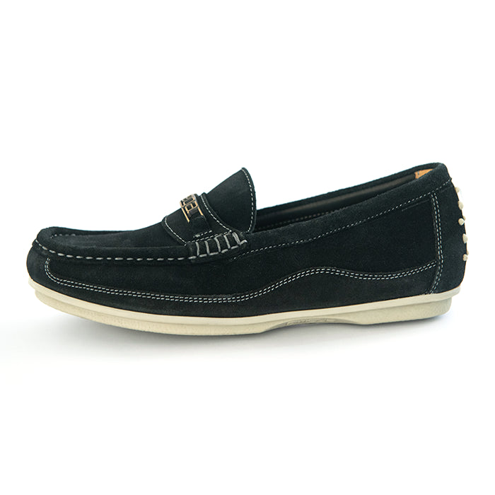 A black suede loafer slip-on shoe with white contrast stitching, a small gold-tone metal accent on the vamp, and a cream-colored sole, shown from a side profile on a white background.