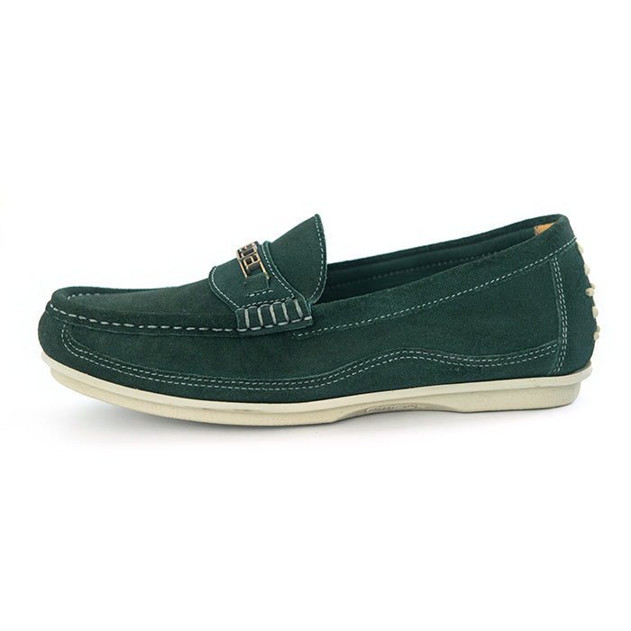 A dark green suede penny loafer with a small gold-tone metal logo on the strap, set against a plain white background.